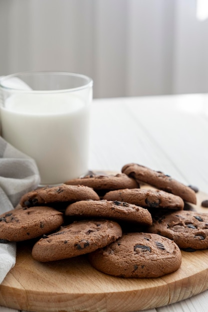 Homemade vegan cookies of cereal and glass of coconut milk on wooden board with kitchen towel Recipe of sugar free cookies with raisins and nuts vegan diet snack Snack or treat for tea or coffee