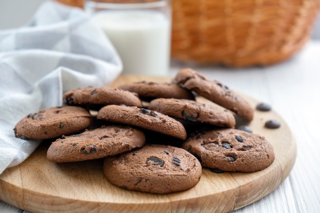 Homemade vegan cookies of cereal on wooden board with kitchen towel and glass of milk Recipe of sugar free cookies with raisins and nuts vegan diet snack Snack or treat for tea or coffee