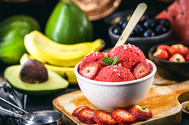 homemade and vegan strawberry ice cream made without milk, with fruits in the background