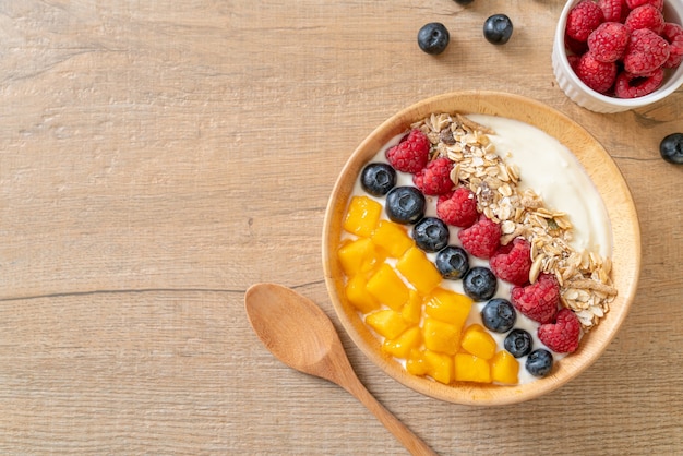 homemade yogurt bowl with raspberry, blueberry, mango and granola - healthy food style