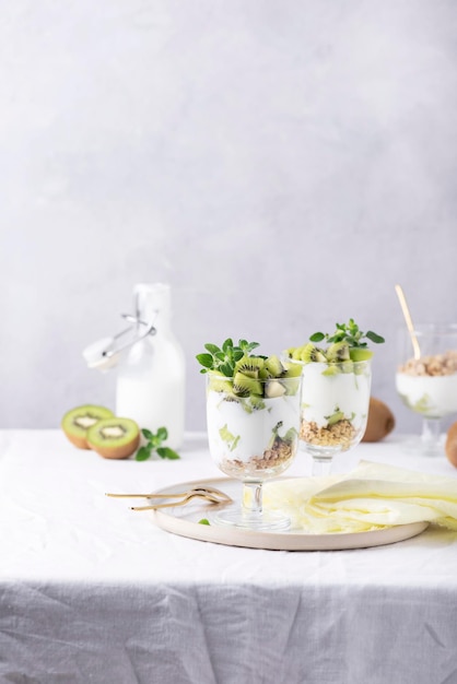 Homemade yogurt with fresh kiwi, muesli and mint on the white background, selective focus image