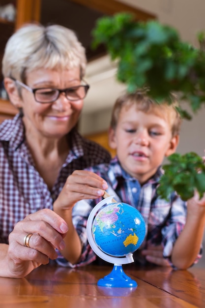 Homeschooling grandmother teaching smart boy child in geography