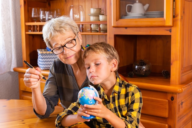 Homeschooling grandmother teaching smart boy child in geography