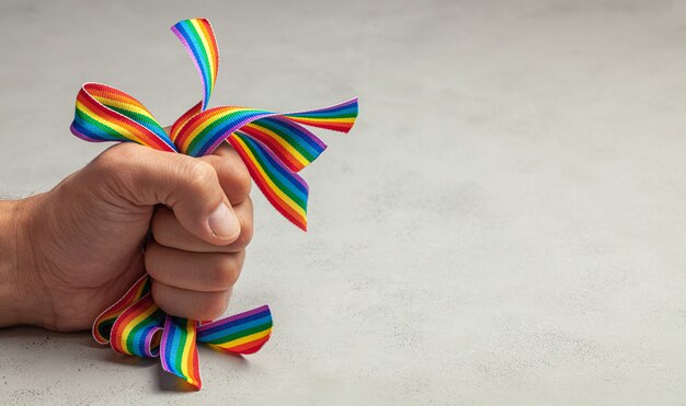 Photo homophobia. stop lgbt pride. man squeezes rainbow lgbt ribbons in his hand.