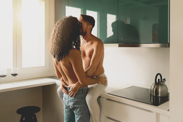 Homosexual couple of males young people hugging in the kitchen