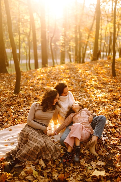 Photo the homosexual family playing with her daughter in the autumn forest the adventure is more fun