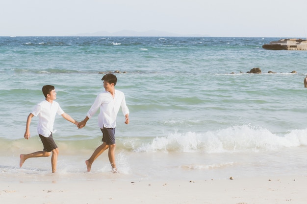 Homosexual portrait young asian couple running together on beach.