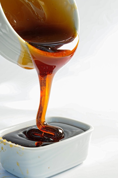 Honey being poured into a white pot freshly produced