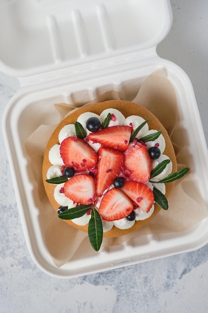 Honey bento cake decorated with cream and fresh strawberries and blueberries