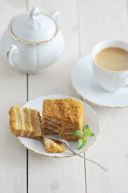 Honey cake and a mint leaf on the saucer with a Golden rim