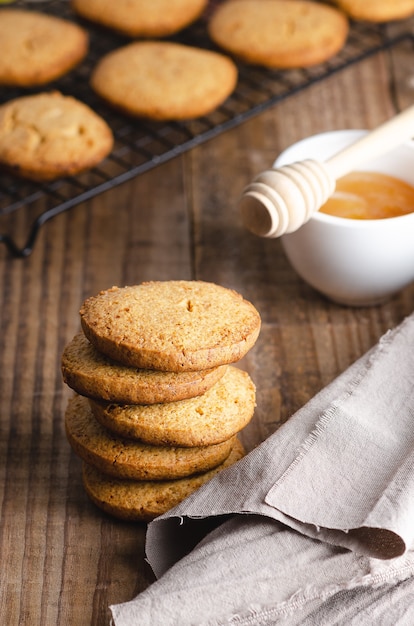 Honey cookies with a beige napkin and a bowl with honey and a honey dipper on a wooden table