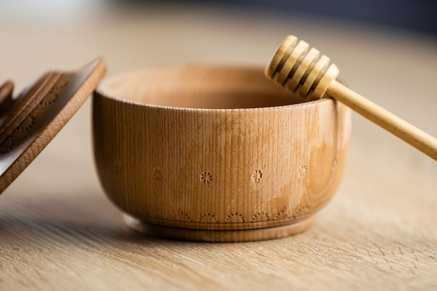 honey in a deep wooden bowl, rustic wooden plate. The wooden spoon drips slowly.