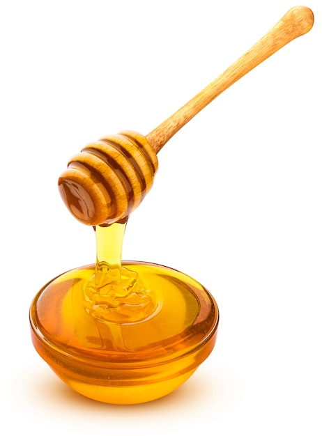 Honey dipper and bowl of pouring honey on white surface