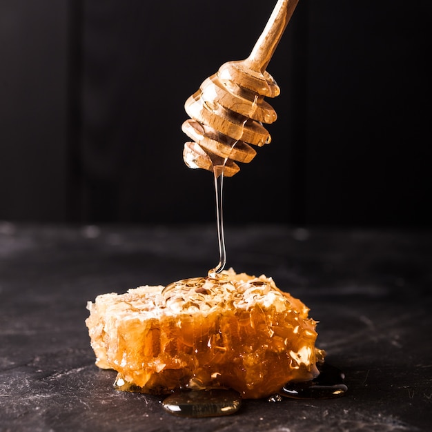 Honey drip and comb over black slate background