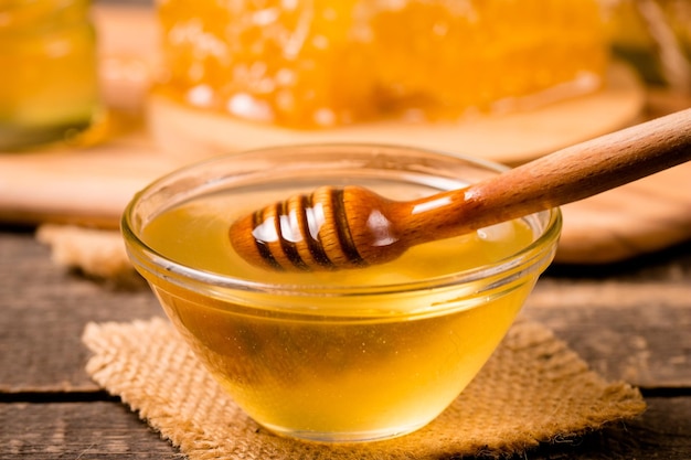 Honey dripping from a honey dipper on wooden rustic background