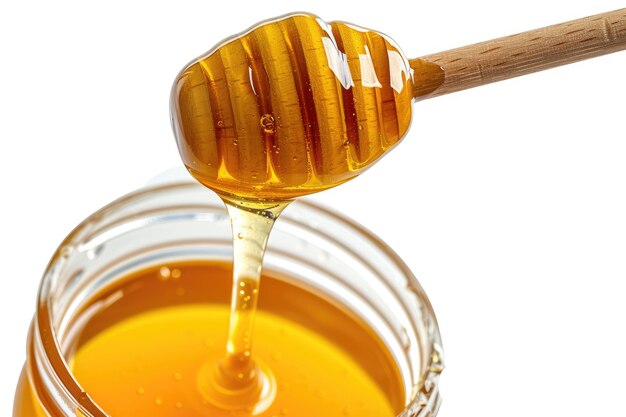 Honey dripping from a wooden honey dipper into a jar isolated on white background