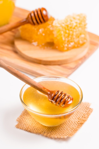 Honey dripping from a wooden honey dipper on white background. Healthy organic food concept.