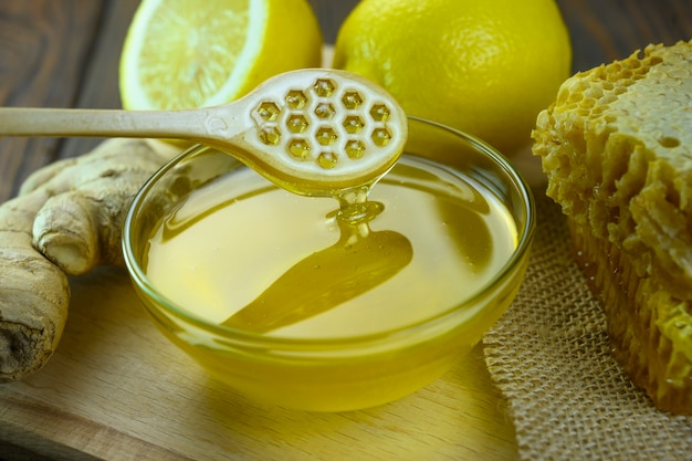 Honey dripping from a wooden spoon into a glass bowl