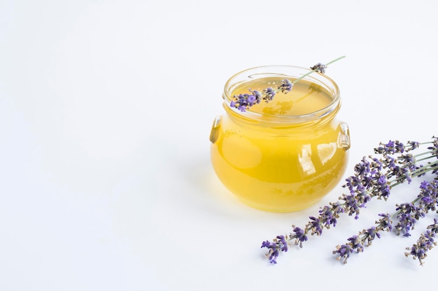 Honey in the glass jar and lavender flower on the white background Closeup Copy space