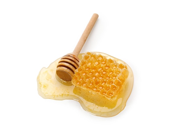 Honey in a honeycomb with wooden stick dipper isolated on white background Natural bee product