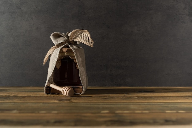 Honey jar decorated on a wooden block with honey stick with background and copy space