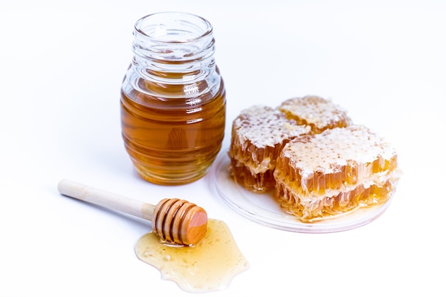 Honey jar, honey and honeycomb on the white background