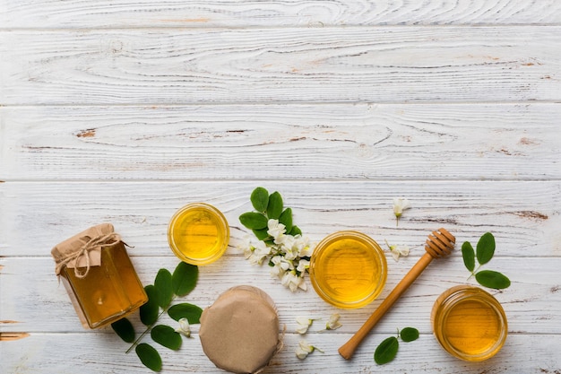 Honey jar with acacia flowers and leaves fresh honey top view flat lay