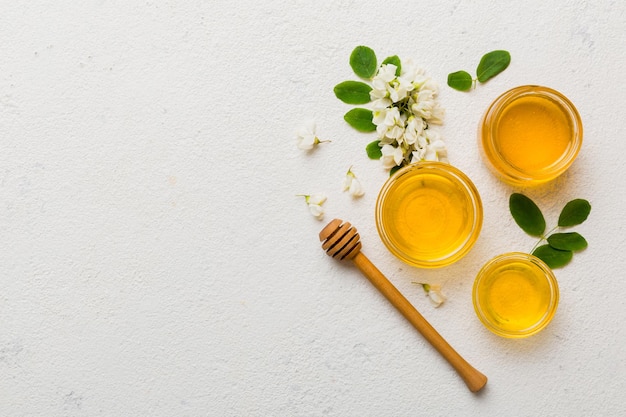 Honey jar with acacia flowers and leaves fresh honey top view flat lay