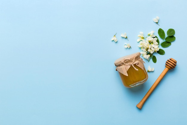 Honey jar with acacia flowers and leaves fresh honey top view flat lay