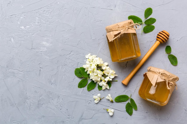 Honey jar with acacia flowers and leaves fresh honey top view flat lay