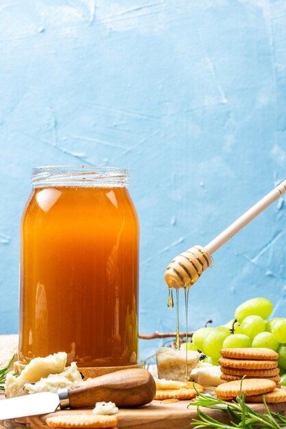 Honey in jar with fruits cheese board and crackers