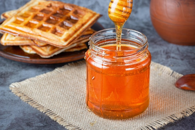 Honey in jar with honey dipper and belgian waffles