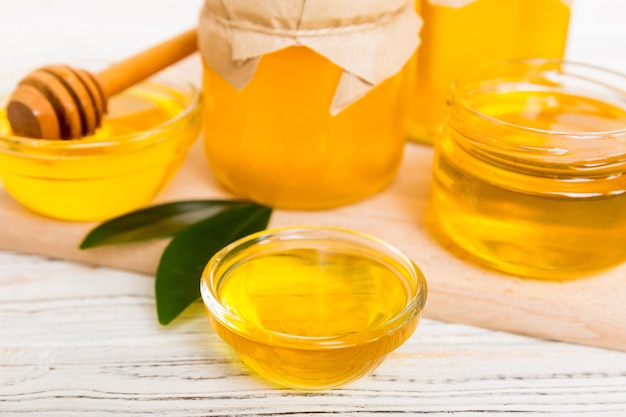 Honey in jar with leaves and honey dipper on colored background top view with copy text