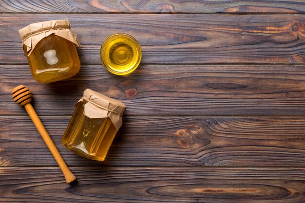 Honey jar with wooden honey dipper on white background top view with copy space Delicious honey bottle