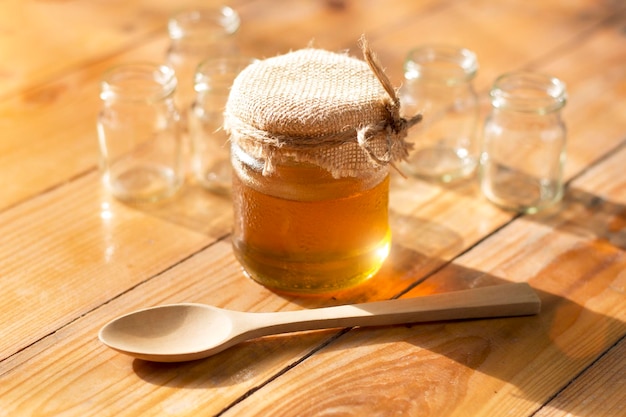 Honey jar and wooden spoon on the table against the orange light of the morning sun