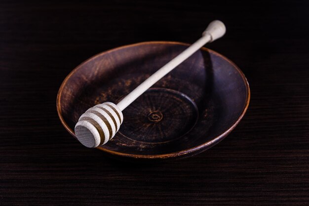 Honey spoon in the ceramic dish on dark wooden table