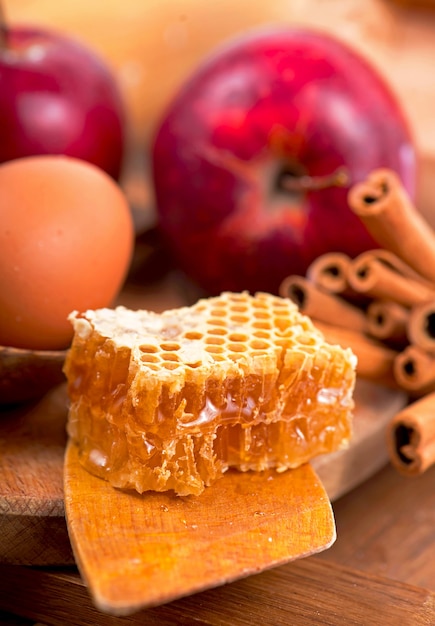 Honey spoon, jar of honey, apples and cinnamon on a wooden background in a rustic style.