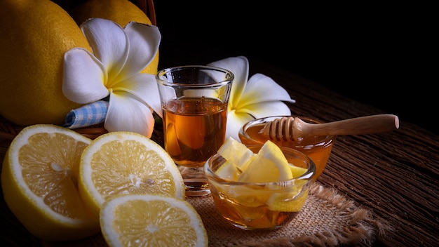 Honey with lemons on wooden table.