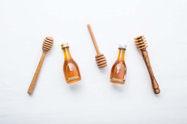 Honey wooden dipper and little honey bottle on white wooden background