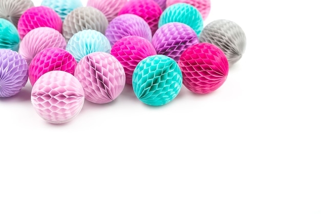 Honeycomb balls decorations border. Pink, lilac and turquoise paper pom pom on a white background. Flat lay.  Holiday concept