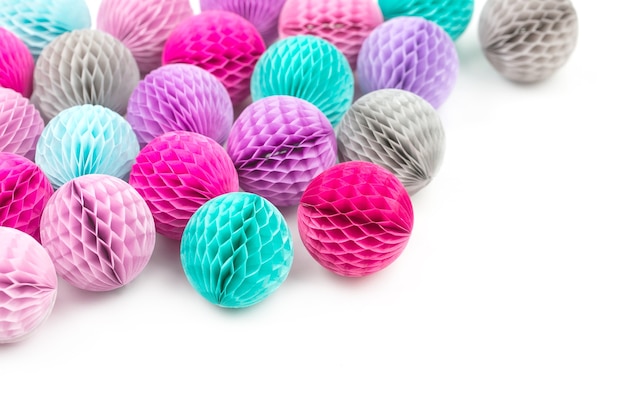 Honeycomb balls decorations border. Pink, lilac and turquoise paper pom pom on a white background. Flat lay.  Holiday concept