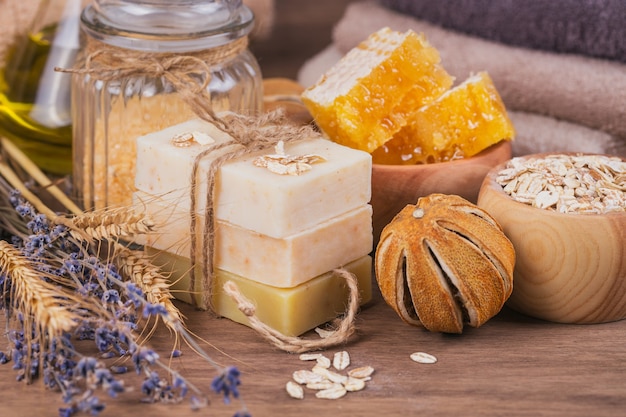 Honeycomb, cosmetic oil, sea salt, oat and handmade soap with honey on rustic wooden background. Natural ingredients for homemade facial and body mask or scrub. Healthy skin care. SPA concept.