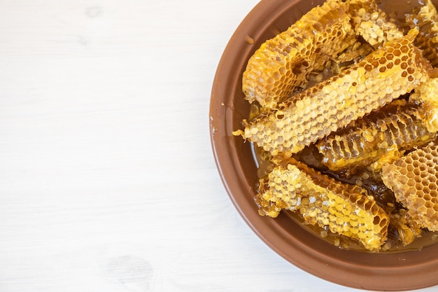 Honeycombs in white plate on the wooden table. Natural organic bee product. Healthy lifestyle.