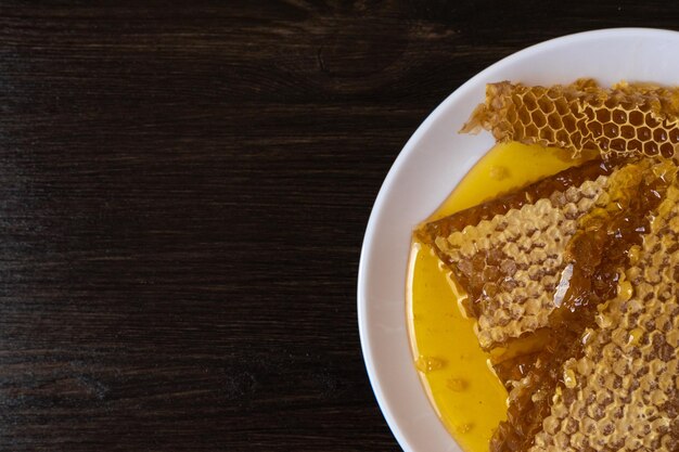 Honeycombs in white plate on the wooden table. Natural organic bee product. Healthy lifestyle.