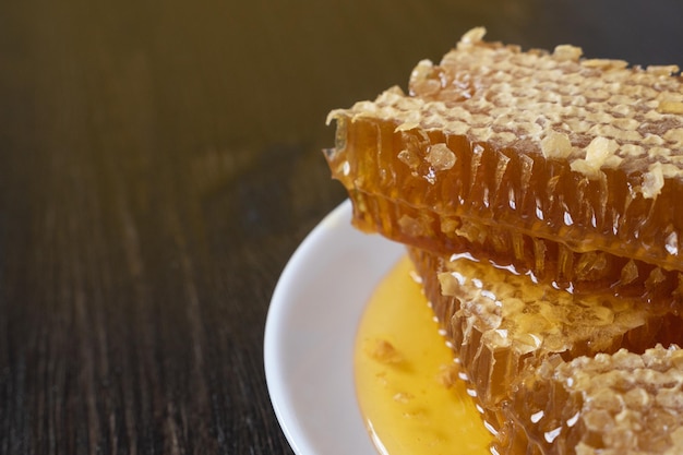 Honeycombs in white plate on the wooden table. Natural organic bee product. Healthy lifestyle.