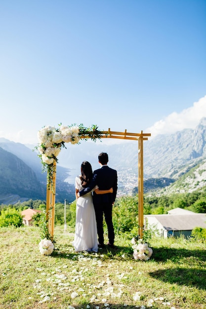 Honeymoon wedding couple travel back view Wedding arch  mountains and sea background in Montenegro Fine art wedding style