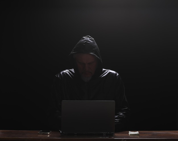 hooded hacker with laptop at night