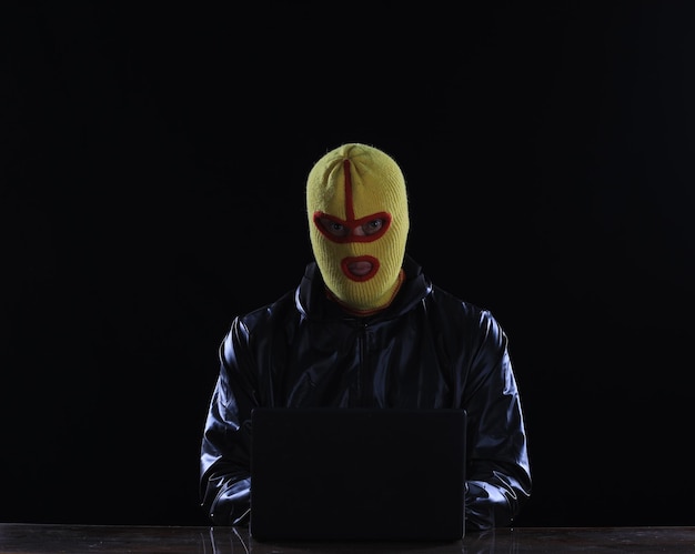 hooded masked hacker with laptop