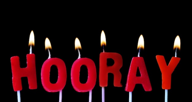 Hooray spellt out in red birthday candles against a black background