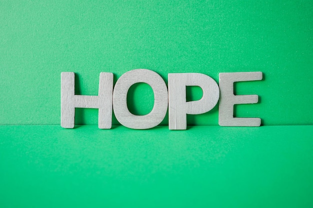 hope word with wooden letters on the green background